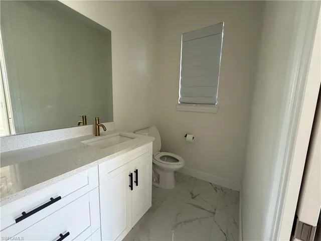 Bathroom vanity featuring a quartz countertop with integrated sink and brass-finish faucet