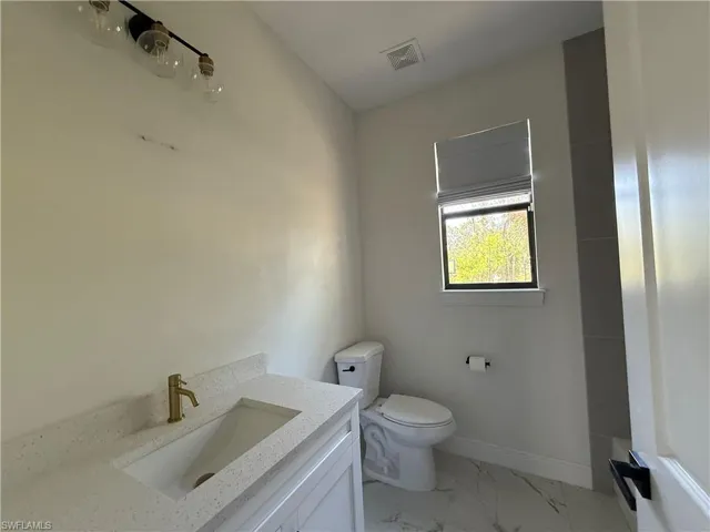 Modern bathroom featuring a white vanity with an integrated rectangular sink, speckled countertop, and a brass-finish faucet