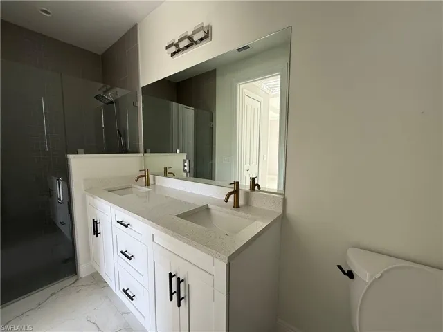 Dual vanity featuring white cabinetry, bronze-finish fixtures, and a white flecked countertop