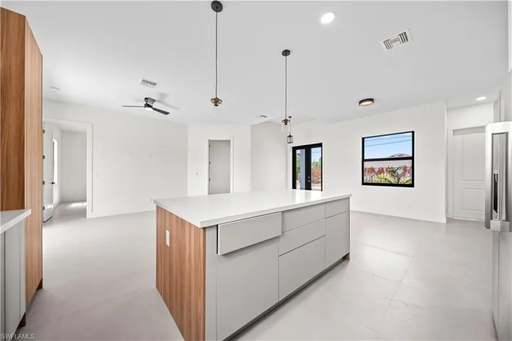 Kitchen with modern cabinets, a center island, hanging light fixtures, high quality fridge, and gray cabinets