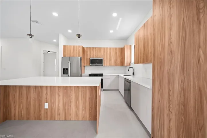 Kitchen featuring modern cabinets, pendant lighting, stainless steel appliances, and a large island