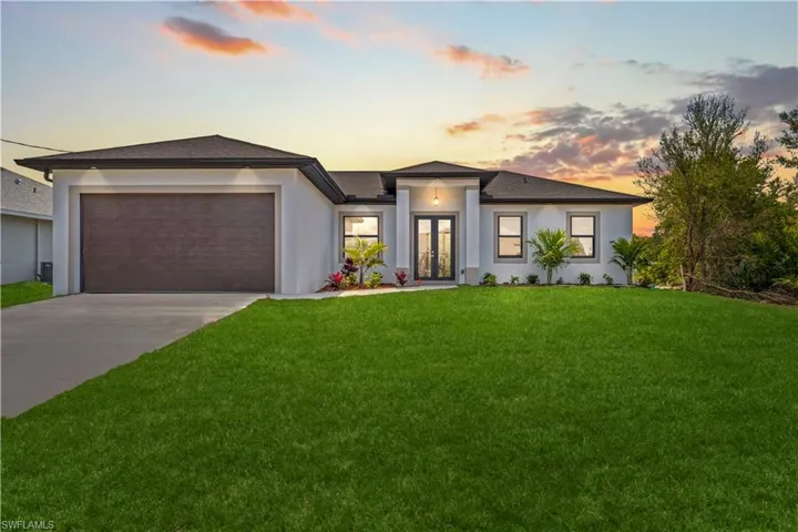 Prairie-style home with a front lawn, french doors, a garage, stucco siding, and concrete driveway