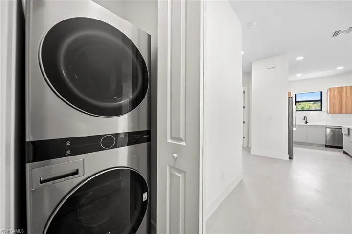 Laundry area featuring stacked washing machine and dryer, recessed lighting, and concrete flooring