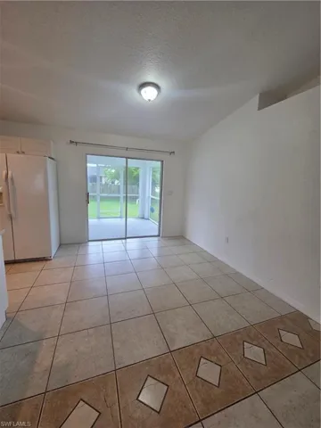 Tile flooring with decorative border, white walls, and a flush mount light fixture