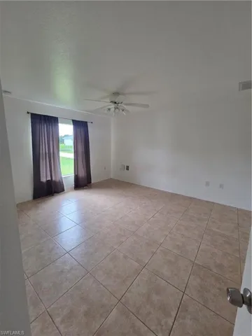 Expansive room featuring tile flooring, ceiling fan with integrated lighting, and multiple windows