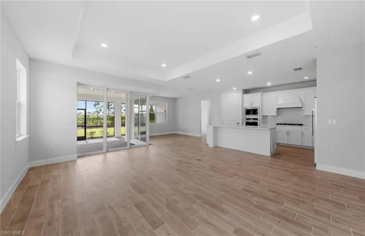 Unfurnished living room featuring light wood-type flooring and a raised ceiling