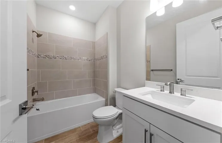 Full bathroom featuring tiled shower / bath, vanity, and toilet