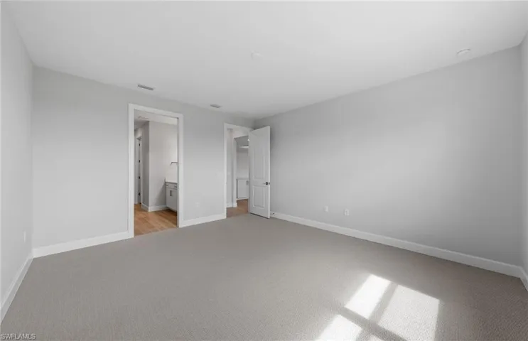 Unfurnished bedroom featuring light colored carpet and ensuite bathroom