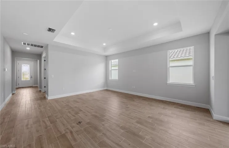 Unfurnished living room with light hardwood / wood-style flooring and a tray ceiling