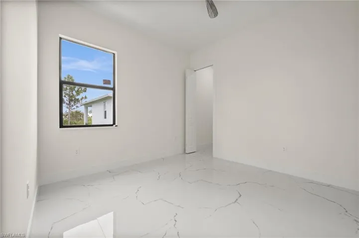 Spare room featuring marble tiled flooring and baseboards