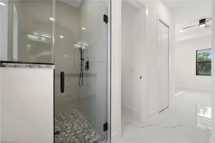 Full bathroom with a stall shower, marble tiled floors, recessed lighting, and a ceiling fan
