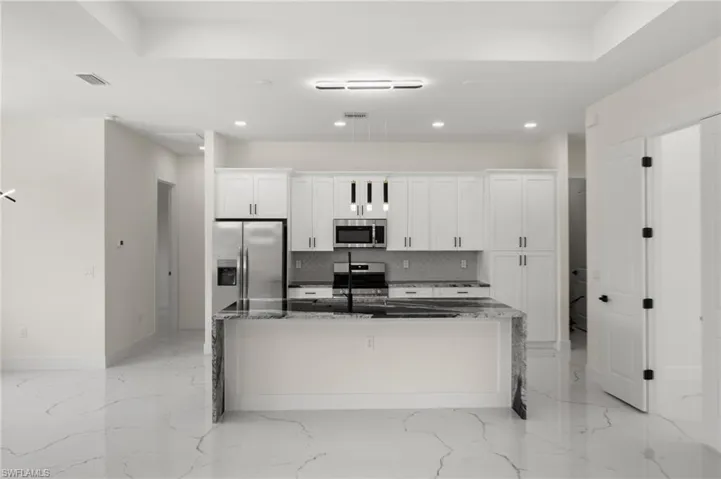Kitchen featuring appliances with stainless steel finishes, white cabinetry, a spacious island, backsplash, and recessed lighting