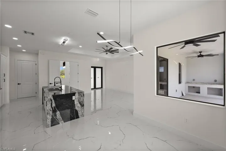 Kitchen featuring a ceiling fan, recessed lighting, light marble finish flooring, open floor plan, and stone counters
