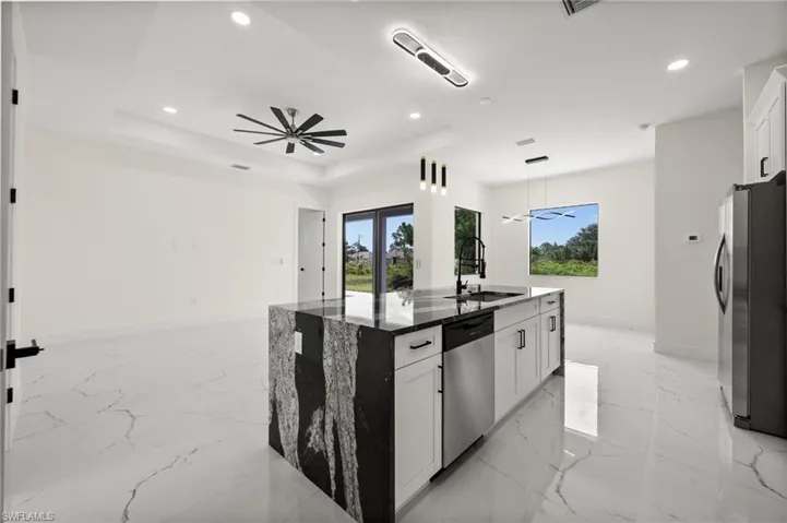 Kitchen featuring appliances with stainless steel finishes, recessed lighting, ceiling fan, an island with sink, and dark stone countertops