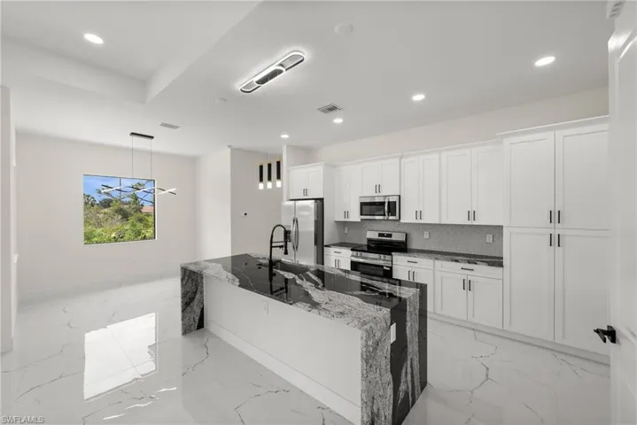 Kitchen with stainless steel appliances, light marble finish floors, white cabinetry, recessed lighting, and decorative backsplash