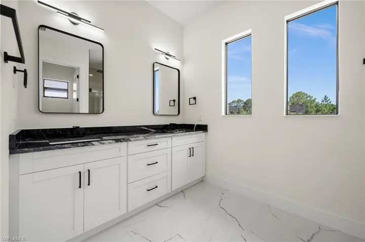 Full bathroom featuring marble look tiles and double vanity