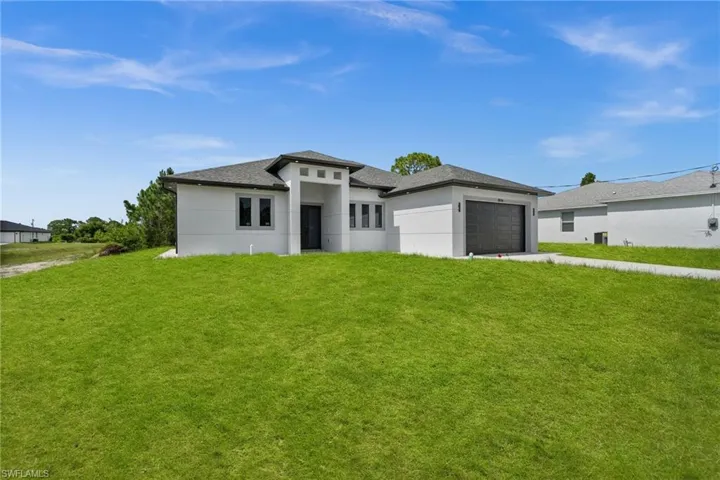 Prairie-style house with a garage, stucco siding, and a front lawn