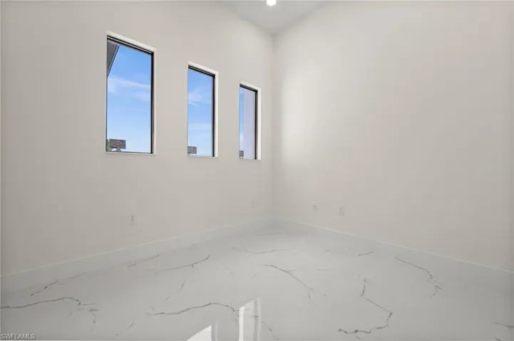 Empty room featuring baseboards and marble tiled floors