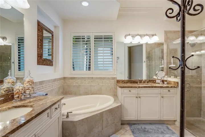 Master bathroom featuring soaking tub, walk-in shower with glass door, separate vanities