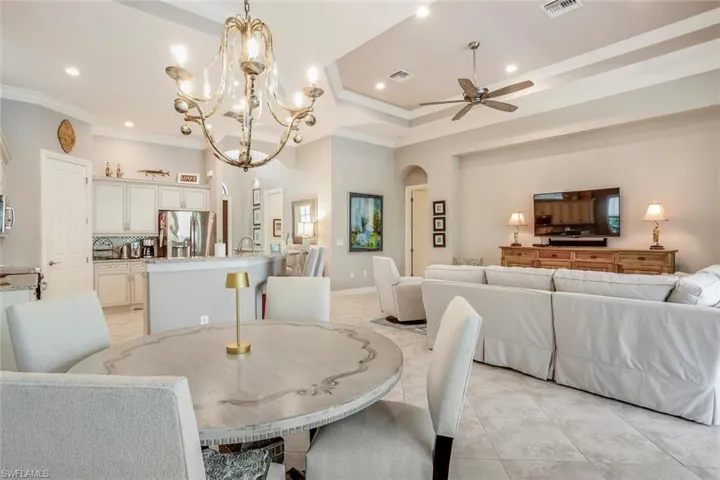 Dining room with arched walkways, a chandelier, light tile patterned flooring, crown molding, and a ceiling fan