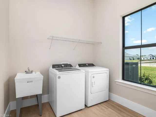 Light and bright laundry room includes utility sink.