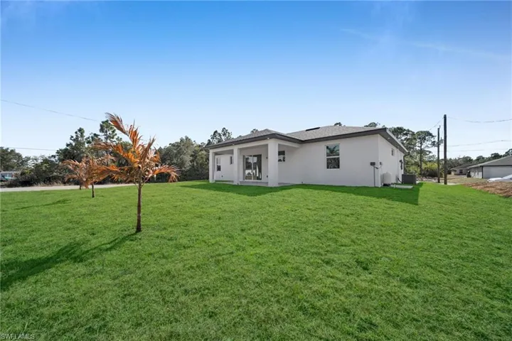 Rear view of property featuring a yard and stucco siding