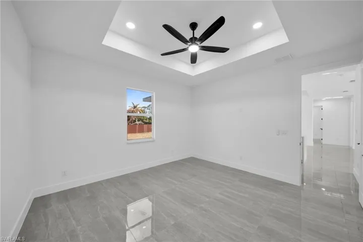 Empty room with ceiling fan, recessed lighting, and a tray ceiling