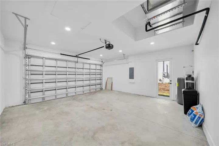 Garage with recessed lighting, water heater, and electric panel