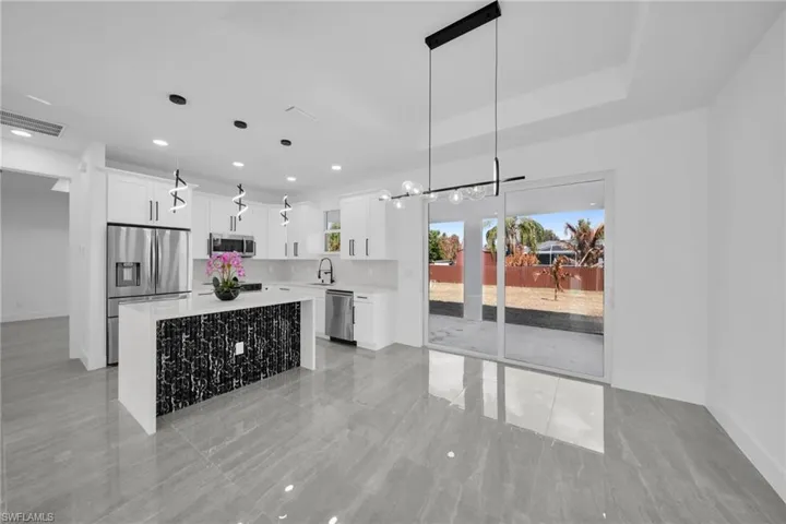 Kitchen with a center island, white cabinetry, stainless steel appliances, and hanging light fixtures