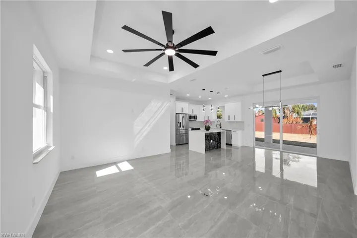 Unfurnished living room with a tray ceiling, a ceiling fan, and recessed lighting