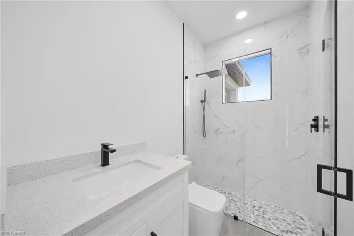 Full bath featuring vanity, a marble finish shower, and recessed lighting