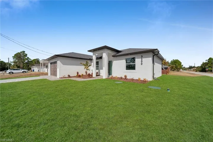 Prairie-style house with concrete driveway, a front yard, stucco siding, and an attached garage