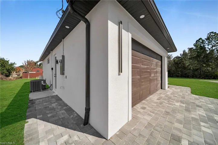 View of home's exterior with a yard, stucco siding, a garage, and a patio