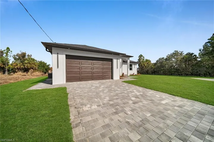 View of front facade with a front lawn, decorative driveway, and stucco siding