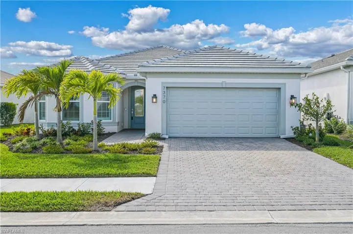 Ranch-style home featuring stucco siding, decorative driveway, a tile roof, and an attached garage