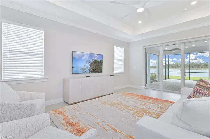 Living area featuring tile patterned floors, ceiling fan, recessed lighting, a raised ceiling, and ornamental molding