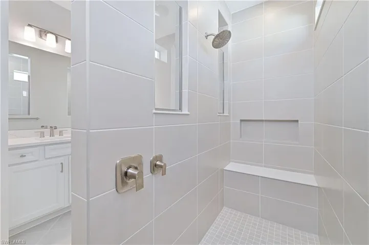 Bathroom featuring tiled shower and vanity