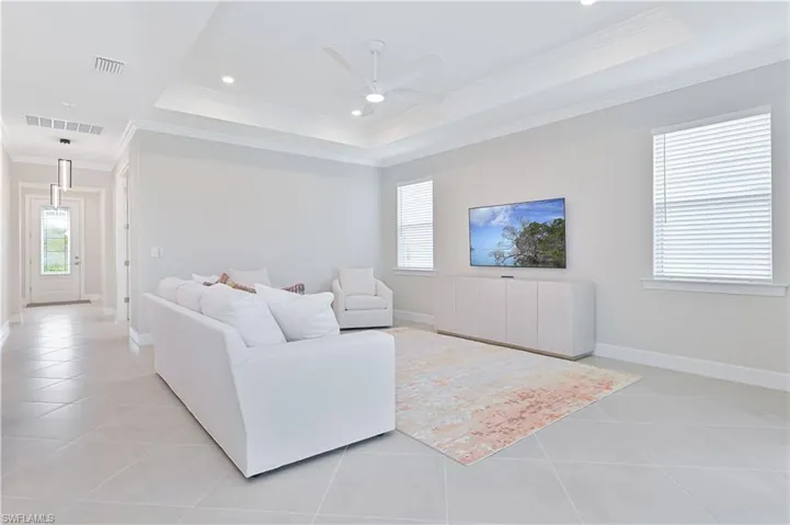 Living area with plenty of natural light, ceiling fan, crown molding, light tile patterned flooring, and a raised ceiling