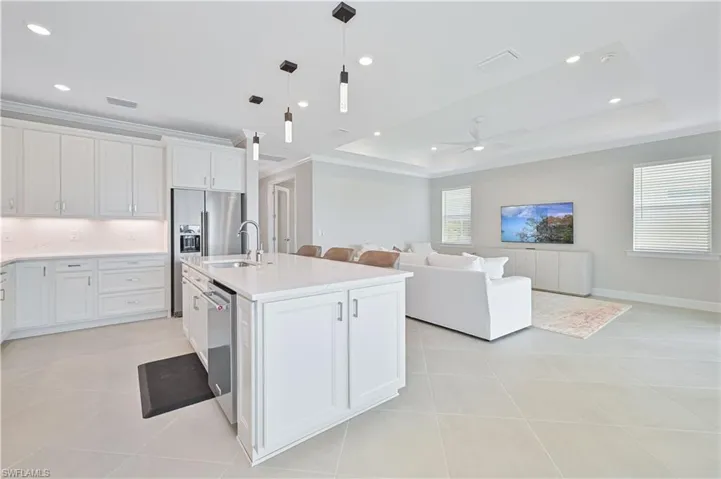 Kitchen featuring white cabinetry, hanging light fixtures, ornamental molding, open floor plan, and light tile patterned flooring