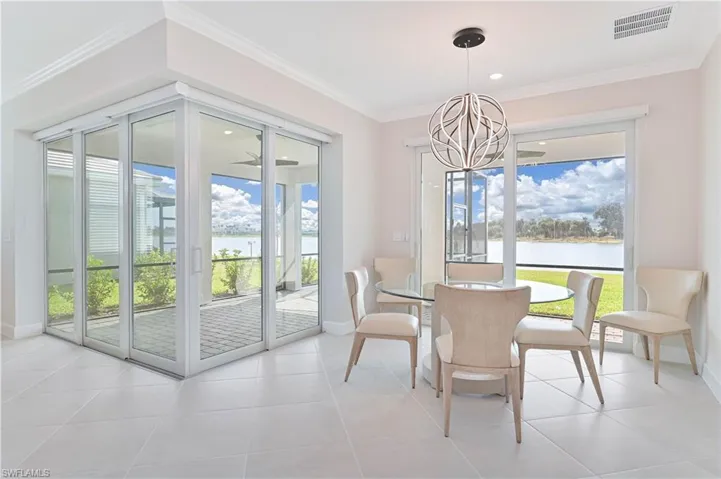 Dining room with a water view, ornamental molding, a chandelier, and light tile patterned floors