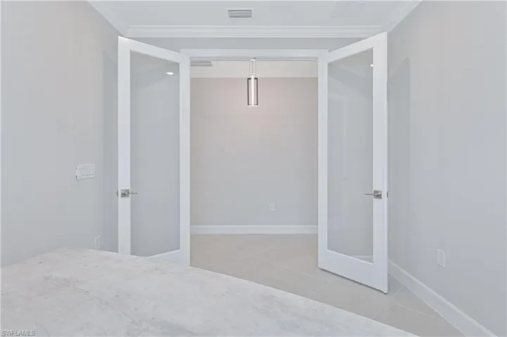Unfurnished bedroom featuring ornamental molding and french doors