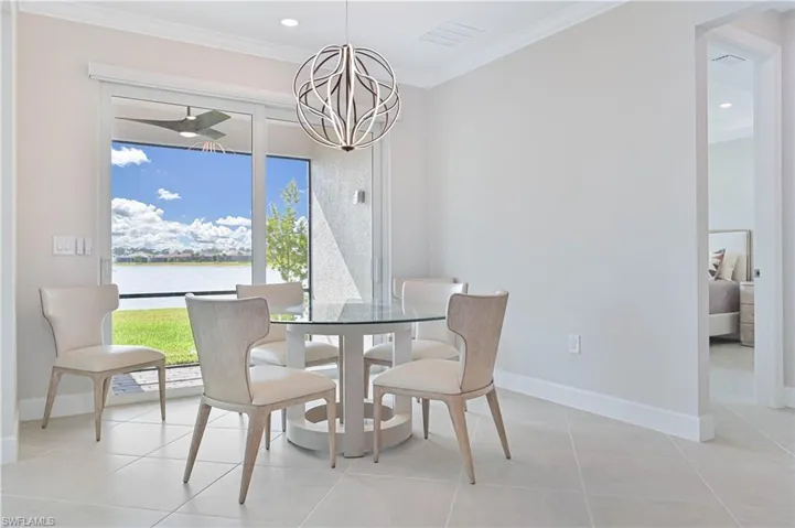 Dining space featuring a chandelier, crown molding, recessed lighting, a water view, and light tile patterned floors