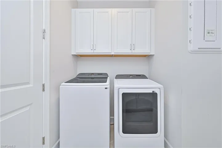 Washroom featuring separate washer and dryer, cabinet space, and electric panel