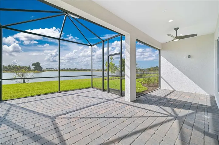 View of patio featuring a sunroom, a ceiling fan, glass enclosure, and a water view