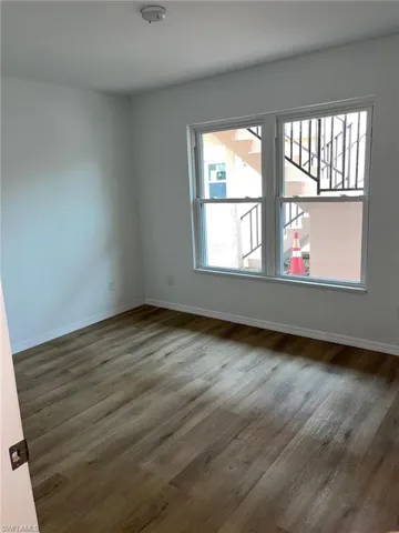 Empty room with dark wood-style flooring and a smoke detector