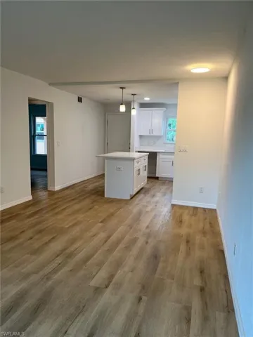 Kitchen with a center island, white cabinets, light wood-style flooring, light countertops, and pendant lighting