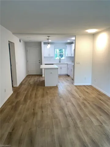 Kitchen with a kitchen island, white cabinetry, light countertops, and light wood-style flooring