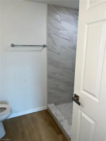 Bathroom with a shower stall and wood finished floors