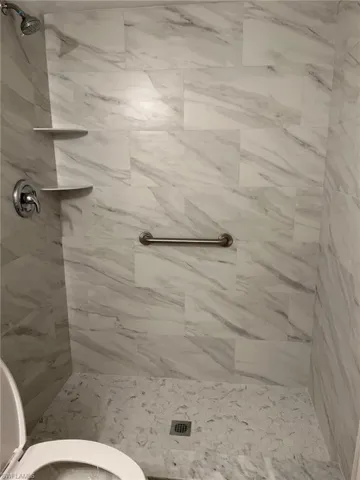 Full bath featuring a shower stall and toilet