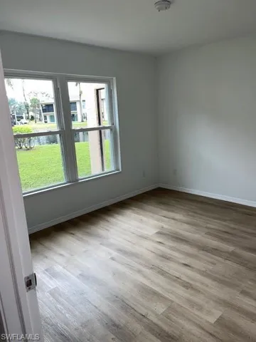Empty room featuring wood finished floors, a water view, and a smoke detector